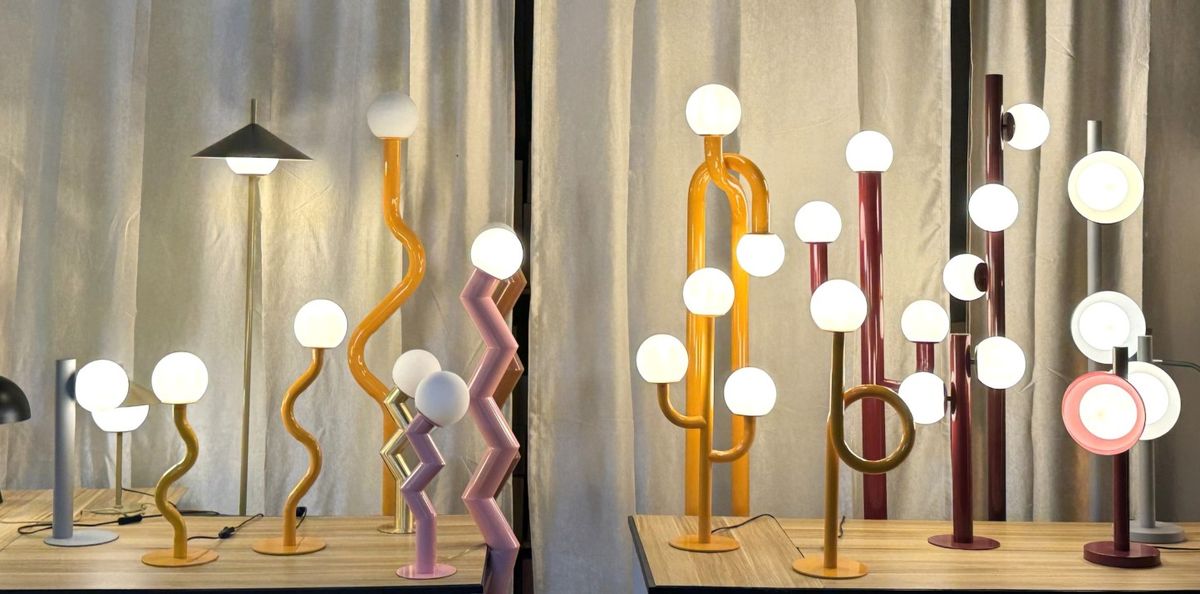 Artistic sculptural table lamps with globe bulbs on curved colorful metal stands in gold, pink and burgundy
